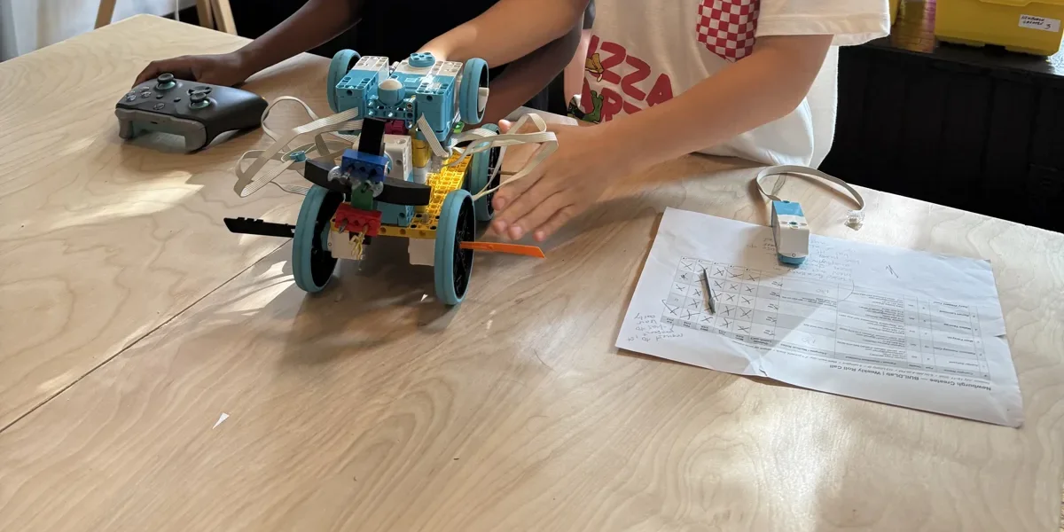A LEGO SPIKE Prime rover built by students at Newburgh Creates, with an Xbox controller beside it on the table