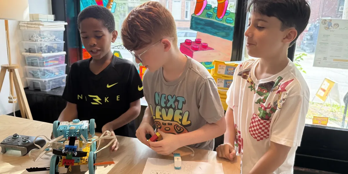 Three students at Newburgh Creates working on a LEGO SPIKE Prime robot at a studio table